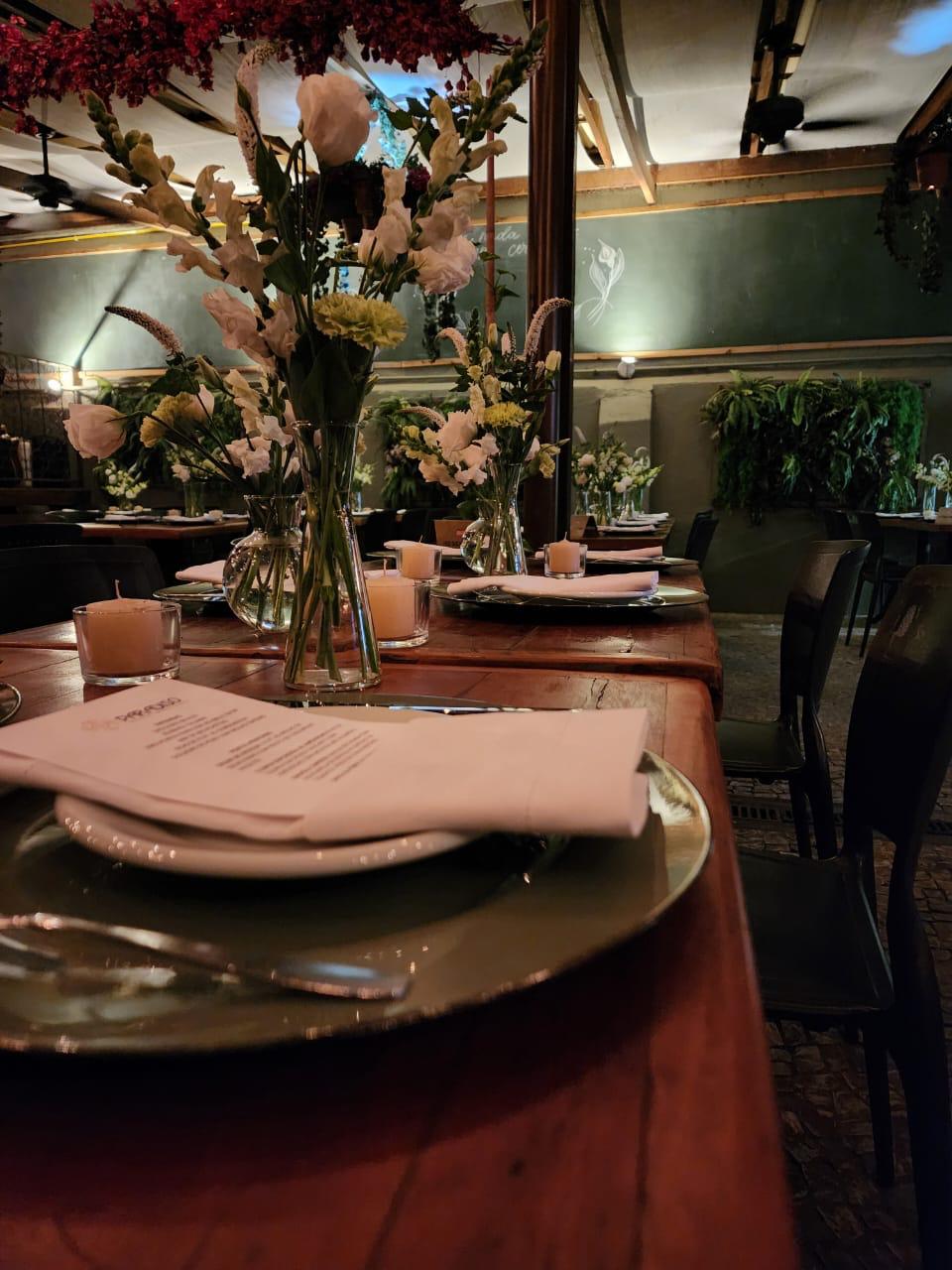 Mesa decorada com flores e velas no ambiente intimista do Paradiso